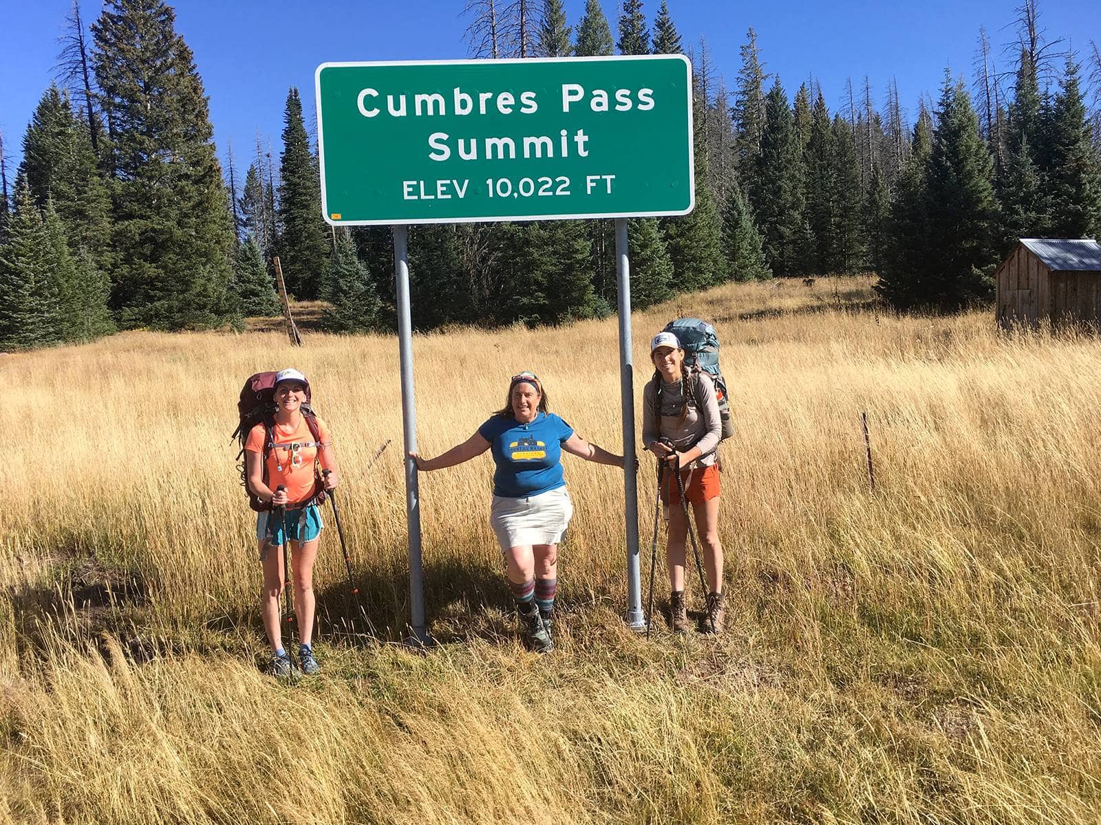 Cumbres Pass Summit sign with smiling hikers