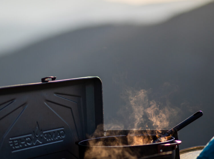 Outdoor cooking with a scenic backdrop.